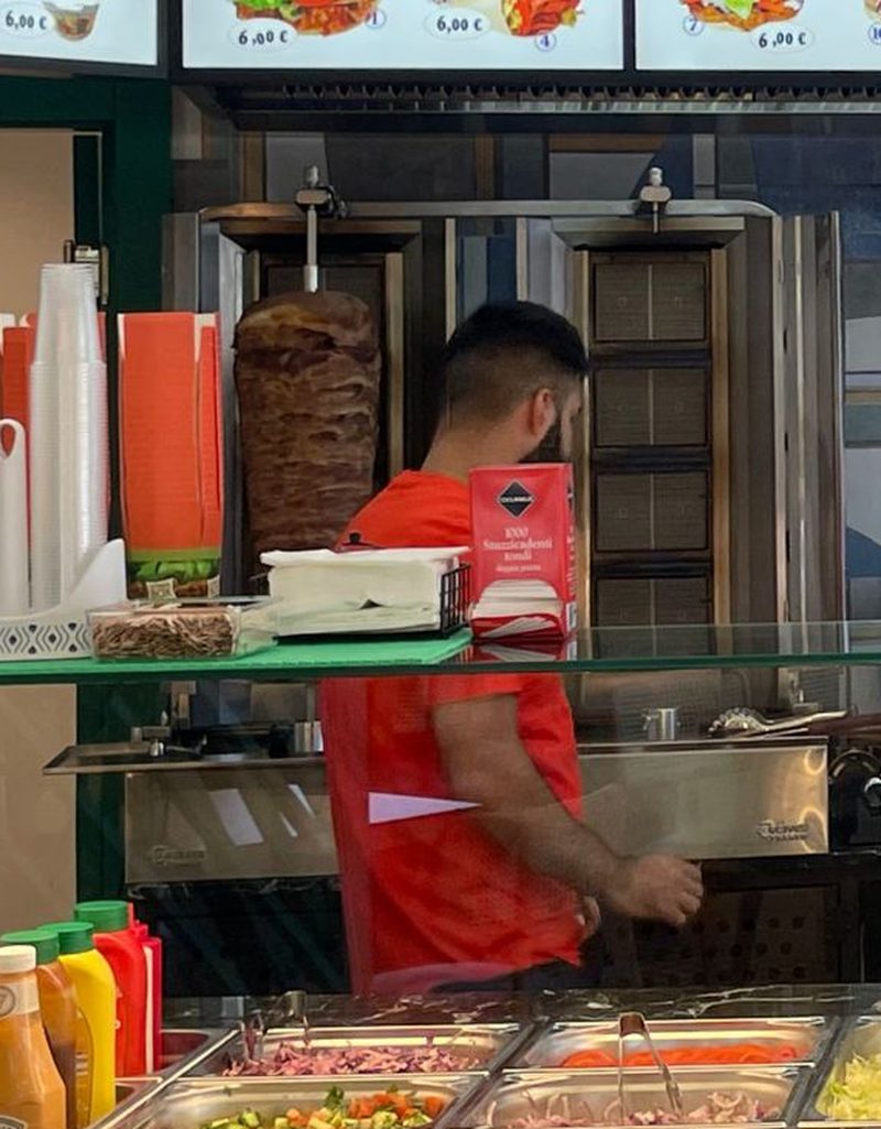 Lo spiedo verticale del döner dietro il banco, con le vaschette delle verdure in primo piano.